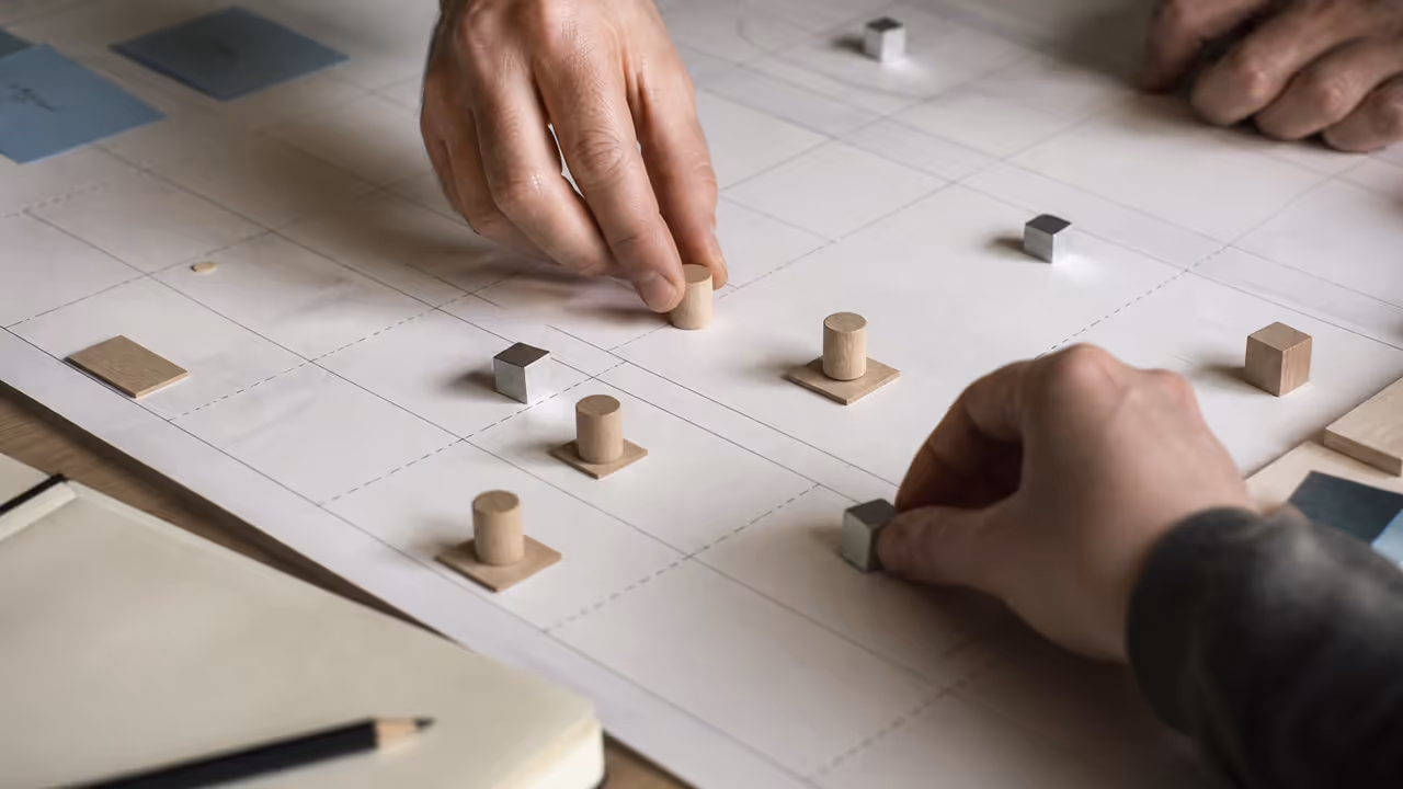 Hands moving wood and metal markers across a service blueprint